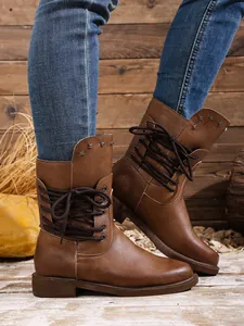 Detailansicht brauner Schnürstiefeletten mit Nietenbesatz und seitlicher Schnürung.