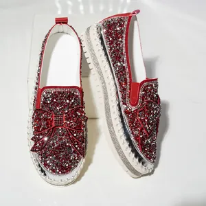 Close-up view of glamorous red rhinestone loafers featuring large bow and white platform soles
