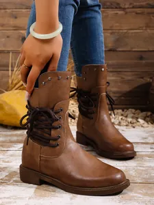 Detailansicht modischer brauner Damen-Stiefeletten mit Metallnieten und dekorativer Schnürung