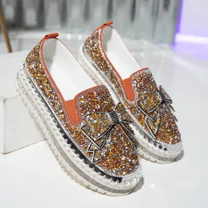 Detailed view of women's loafers featuring sparkling orange rhinestones and a large bow