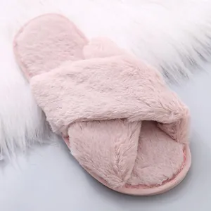 Close-up of soft pink fuzzy slippers with cross-strap design and plush texture
