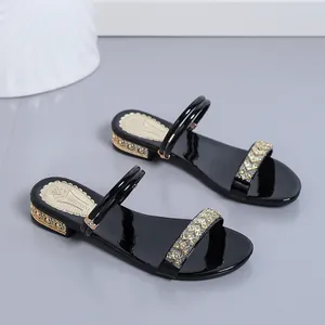 Detalle de sandalias negras de tacón medio con elegantes adornos de pedrería y oro