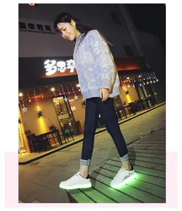Close-up of white LED luminous shoes with green glowing soles worn by a model at night.