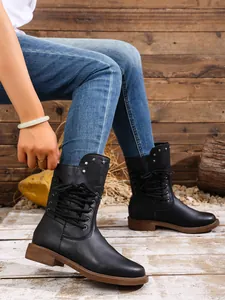 Detailansicht der schwarzen Schnürstiefel mit beschlagener Manschette und flacher Sohle