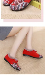 Detailed view of red embroidered winter shoes with warm fur lining and floral patterns.