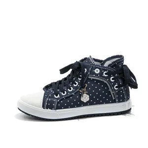 Detail view of navy polka dot high-top sneakers with floral charm and side zipper.