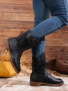 Modische schwarze Damen-Schnürstiefeletten mit Nietendetails in einer rustikalen Außenumgebung