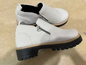 Detailed view of modern white women's ankle boot with side zipper and chunky lug sole