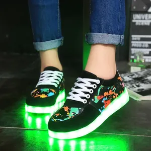 Close-up of stylish black graffiti LED light-up sneakers glowing with a bright green light