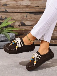 Nahaufnahme von braunen Retro-Wildleder-Loafern mit bunten Perlendetails am Fuß getragen