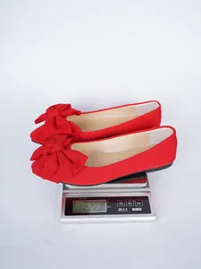 Detail view of red bowknot flat shoes on a digital scale showing weight of 222.8g.
