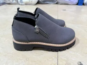 Close-up of grey suede Martin boots featuring a side zipper and durable lug sole