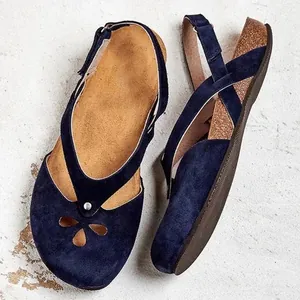 Detailed view of navy blue suede flat sandals featuring a floral cutout and back strap