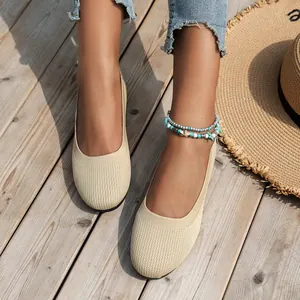 Close-up view of beige knitted ballet flats worn on feet with a summer beach vibe