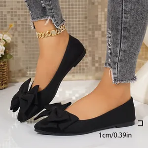 Side view of black square-toe flat shoes featuring a large decorative bow