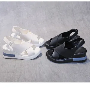 Close-up of black and white platform wedge sandals with cross-straps and buckles.