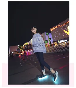 Stylish black LED light-up sneakers with glowing blue soles in a night city square
