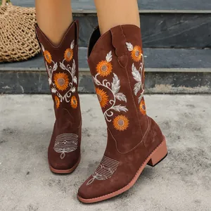 Detail shot of brown cowboy boots with intricate sunflower embroidery and block heel.