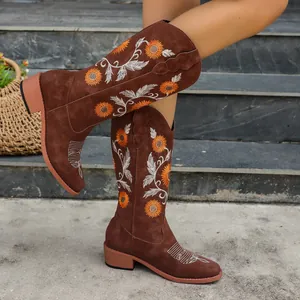 Close-up of brown suede tall boots with intricate orange sunflower embroidery detail