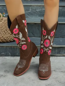 Detailed view of intricate pink floral embroidery on brown suede western cowboy boots