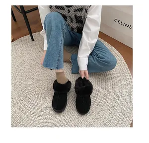 Top-down view of black faux fur lined winter slippers worn by a model on a woven rug