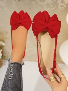 Close-up of red ballet flats with a stylish large bow, showing the material and design.