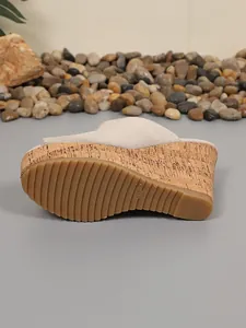 Vista detallada de la suela de una sandalia de cuña beige con textura de corcho