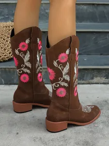 Close-up of pink floral embroidery on brown western tall boots with sturdy block heels