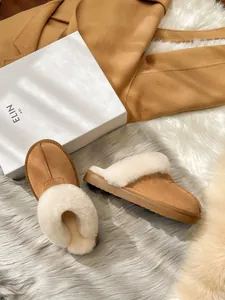 Detailed view of warm camel suede slippers featuring thick white faux fur lining and collar