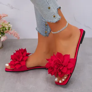Detailed view of red flat sandals featuring a large layered flower and square toe