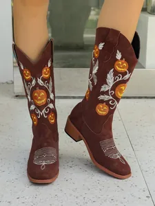 Macro view of brown suede tall cowboy boots featuring intricate festive pumpkin embroidery