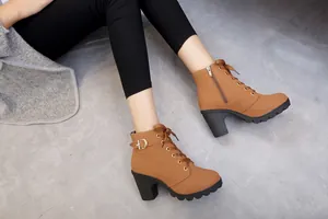 Close-up shot of tan lace-up high heel ankle boots with a thick platform sole.
