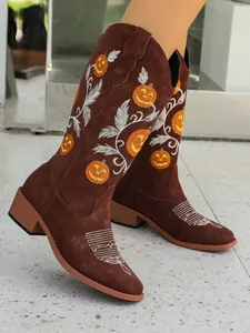 Detailed shot of brown western boots featuring festive orange pumpkin embroidery accents.