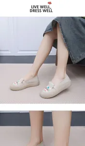 Detailansicht von beige bestickten Slippern aus Stoff am Modell