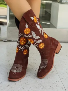 Detail showing festive Halloween pumpkin and vine embroidery on brown suede mid-calf boots