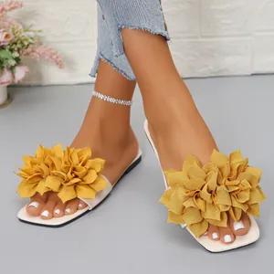 Detailed view of women's flat sandals with vibrant yellow fabric flower decoration.