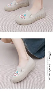 Detailansicht der bestickten chinesischen Stoffschuhe mit Löwentanz-Motiv in Beige