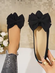 Close-up of elegant black square toe flats featuring an oversized bow detail