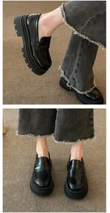 Detailed close-up view of black platform loafers paired with stylish frayed denim jeans