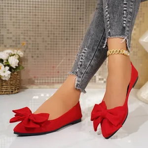 Close-up of vibrant red pointed-toe flat shoes featuring a decorative oversized bow detail.