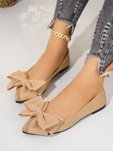 Detailed shot of beige glittery flat shoes featuring a large stylish bow and square toe