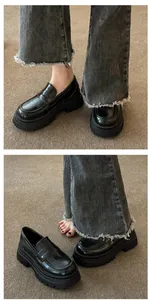 Detail view of black platform loafers with chunky soles paired with fringe denim jeans