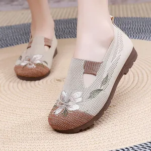 Detailed view of beige knitted loafers with elegant floral embroidery on a straw mat