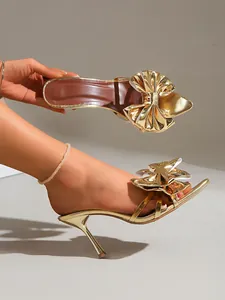 Vue détaillée de l'élégante mule à talons hauts dorée ornée d'un grand nœud décoratif chic