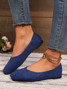 Close-up detail of stylish blue suede-like flat shoes worn with jeans and a gold anklet