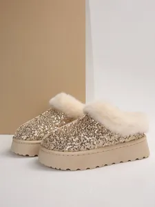 Detalle de botas de plataforma con lentejuelas doradas y ribete de suave piel sintética.