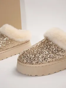 Primer plano de zapatos de plataforma con lentejuelas doradas y ribete de piel sintética crema.