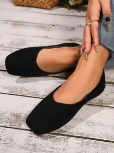 Close-up detail of black suede square toe flat shoes on model with stylish accessories