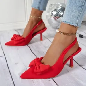 Detailansicht eleganter roter High Heels mit dekorativer Schleife und spitzer Zehenpartie.
