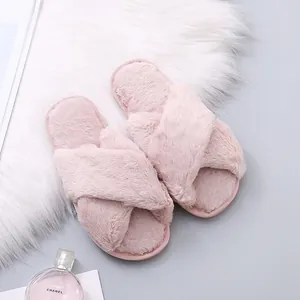 Close-up of pink fuzzy cross-strap slippers with soft plush texture on white fur rug.